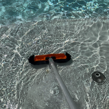 Brushing the walls, steps, and corners of each pool to prevent algae growth in St George, Utah